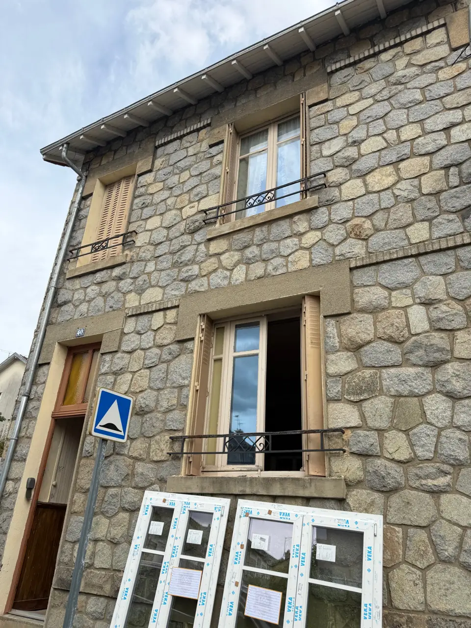 Maison en pierre avant le remplacement des fenêtres, menuiseries neuves livrées au pied de la façade