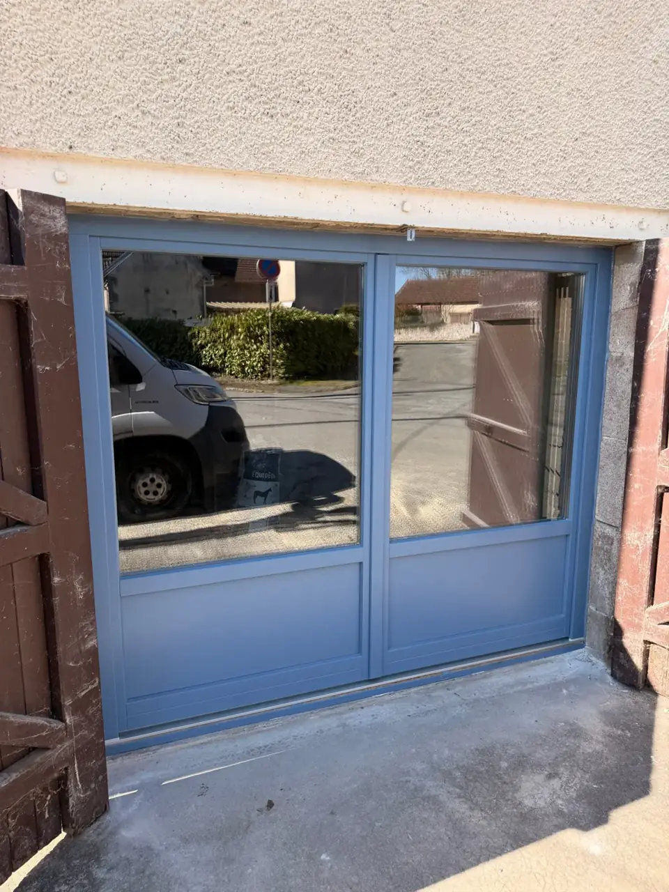 Portail en aluminium peint en bleu avec double vantaux et vitrage.
