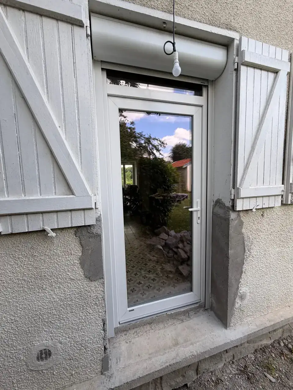 Portes en PVC avec volets battants en bois blanc, installation extérieure moderne.
